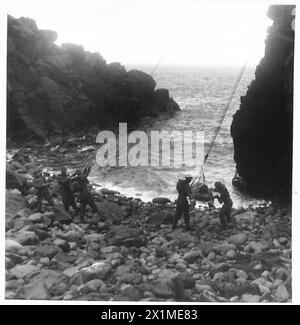 NOUVELLE MÉTHODE DE SAUVETAGE DES VICTIMES DE FALAISE - le voyage terminé. Le groupe de brancard abaisse le patient sur la plage pierreuse pour des soins médicaux ou embarquement par bateau, armée britannique Banque D'Images