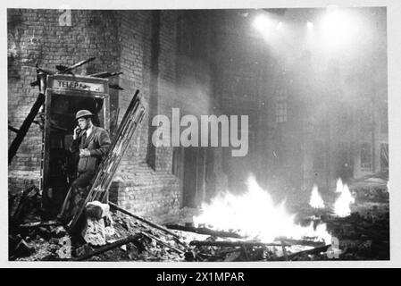 ACTEURS DE CINÉMA AFS : LE TOURNAGE DE 'L'HISTOIRE INÉDITE' AUX STUDIOS DE CINÉMA DE DENHAM, DENHAM, BUCKINGHAMSHIRE, ANGLETERRE, ROYAUME-UNI, 1941 - pendant le tournage du film de la Two Cities film Company 'Unpublished Story', tourné aux studios Denham, l'acteur Richard Greene passe un appel dans une cabine téléphonique endommagée entourée de gravats et de débris. Des zones de feu peuvent être vues en bas de la rue. Le film est réalisé par Harold French et se déroule pendant le Blitz sur les docks de Londres en 1940, Banque D'Images