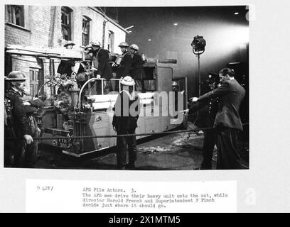 ACTEURS DE CINÉMA AFS : LE TOURNAGE DE 'L'HISTOIRE INÉDITE' AUX STUDIOS DE CINÉMA DE DENHAM, DENHAM, BUCKINGHAMSHIRE, ANGLETERRE, ROYAUME-UNI, 1941 - les hommes de l'AFS de la brigade de pompiers d'Uxbridge conduisent leur moteur sur le plateau du film de la Two Cities film Company 'Unpublished Story' aux studios de Denham. Le directeur Harold French et le surintendant F Finch (à droite) décident exactement où l'appareil incendie doit aller. Le film met en vedette Richard Greene et Valerie Hobson. Il se déroule pendant le Blitz sur les quais de Londres en 1940, Banque D'Images