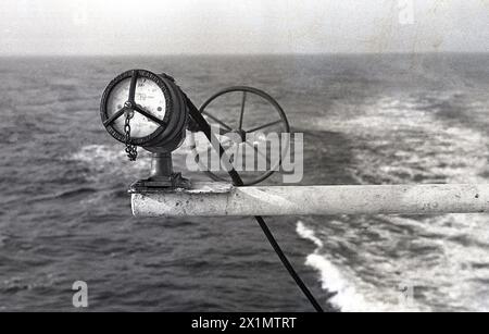 Années 1950, historique, sur le côté du paquebot MS Kungsholm un poteau métallique tenant une jauge de pression maritime + roue. Le libellé de la jauge se lit comme suit : « dévisser, transporter par chaîne jamais par câble ». Construit en 1953 pour Svenska Amerika Linien (SAL), le paquebot/bateau de croisière, offrait des traversées transatlantiques de Gothenburg à New York pendant l'été et des croisières de luxe pendant d'autres parties de l'année. Banque D'Images