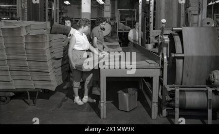 Années 1950, travailleuses historiques sur un banc de travail sur l'atelier de production d'une papeterie de la Crown Zellerbach Corporation, WA, États-Unis. Les femmes trient sont de grands sacs en papier, connus sous le nom de sacs plats, utilisés pour les courses et les livraisons de nourriture, dans ce cas des sacs imprimés pour un vendeur de tomates. Banque D'Images