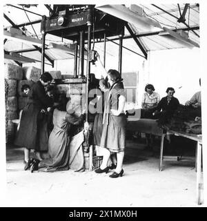 ROYAL ORDINANCE CORPS : RETURNED STORES DEPOT - au travail autour de la machine à balles, montrant les vêtements des soldats reconditionnés en balles prêts pour la réédition, armée britannique Banque D'Images