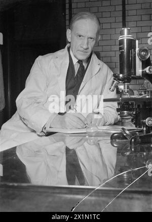 PÉNICILLINE PASSÉ, PRÉSENT ET FUTUR : LE DÉVELOPPEMENT ET LA PRODUCTION DE PÉNICILLINE, ANGLETERRE, 1944 - le professeur Sir Robert Robinson est assis à côté de son microscope dans un laboratoire de l'Université d'Oxford. Sir Robert, avec le Dr Chain et le Dr Abraham à l'École de pathologie, essaie de fabriquer de la pénicilline synthétique. Il est professeur Waynflete de chimie à Oxford depuis 1930 et membre du Comité du Conseil privé pour la recherche scientifique et industrielle depuis 1940. Banque D'Images