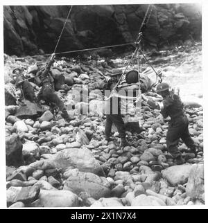 NOUVELLE MÉTHODE DE SAUVETAGE DES VICTIMES DE FALAISE - le voyage terminé. Le groupe de brancard abaisse le patient sur la plage pierreuse pour des soins médicaux ou embarquement par bateau, armée britannique Banque D'Images