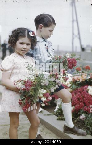 Deux enfants déposent des fleurs sur le monument aux morts de Courseulles lors des célébrations de la Bastille Day le 14 juillet 1944. Courseulles fut la première ville libérée par les Alliés. Banque D'Images