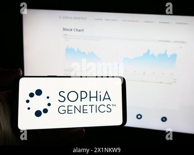 Personne tenant un téléphone portable avec le logo de la société suisse de logiciels de santé Sophia Genetics sa en face de la page Web de l'entreprise. Concentrez-vous sur l'affichage du téléphone. Banque D'Images