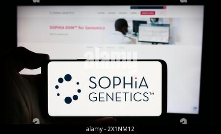 Personne tenant un téléphone portable avec le logo de la société suisse de logiciels de santé Sophia Genetics sa en face de la page Web de l'entreprise. Concentrez-vous sur l'affichage du téléphone. Banque D'Images