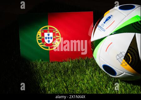 LEIPZIG, ALLEMAGNE, 17 AVRIL 2024 : drapeau national du Portugal et ballon officiel de football de l'Euro 2024 en Allemagne placé sur l'herbe verte. B Banque D'Images