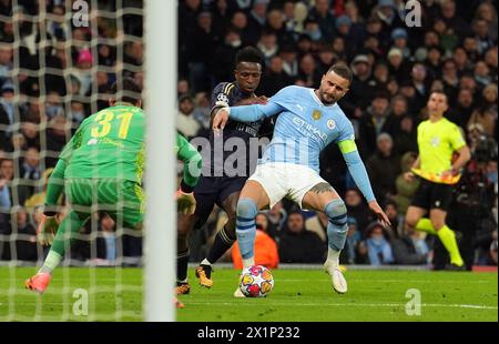 Kyle Walker de Manchester City retient le ballon au gardien de but Ederson (à gauche) alors qu'il retient Vinicius Junior du Real Madrid lors du match de deuxième manche en quart de finale de l'UEFA Champions League au stade Etihad de Manchester. Date de la photo : mercredi 17 avril 2024. Banque D'Images