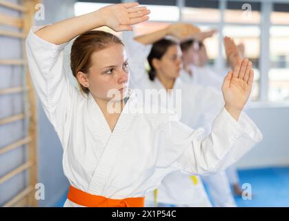 Karatéka adolescent pratiquant les coups de poing pendant le kata à l'entraînement de groupe Banque D'Images