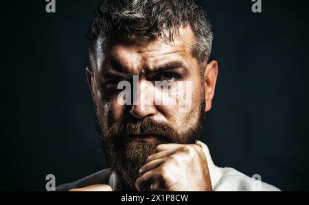 Gros plan portrait de l'homme de karaté sérieux en kimono en position de combat. Homme barbu pratiquant l'aïkido au gymnase. Combattant de karaté se préparant à la compétition Banque D'Images