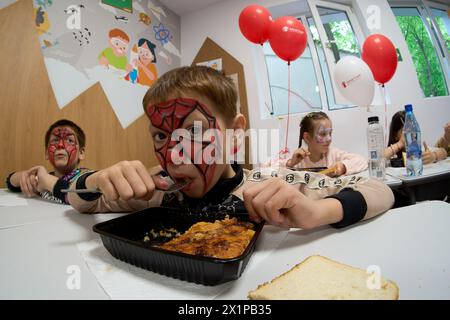 Bucarest, Roumanie. 17 avril 2024 : le garçon ukrainien Radu mange son repas lors de l'ouverture du Centre de jour pour les enfants réfugiés d'Ukraine dont les mères travaillent ou veulent trouver un emploi. Le centre est ouvert par la Fondation Save the Children Roumanie pour 40 enfants, âgés de 6 à 11 ans, et pour soutenir les mères réfugiées d'Ukraine afin qu'elles puissent laisser leurs enfants en toute sécurité pendant qu'elles sont au travail, compte tenu du fait que trois parents ukrainiens sur cinq ne pouvaient pas trouver d'emploi en Roumanie, la plupart d'entre eux invoquant la barrière de la langue ou la nécessité de s'occuper d'un membre de la famille. Depuis l'apparition de Banque D'Images