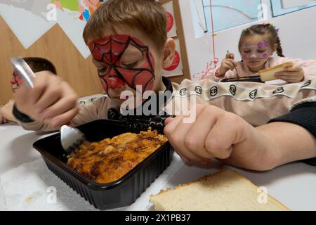 Bucarest, Roumanie. 17 avril 2024 : le garçon ukrainien Radu mange son repas lors de l'ouverture du Centre de jour pour les enfants réfugiés d'Ukraine dont les mères travaillent ou veulent trouver un emploi. Le centre est ouvert par la Fondation Save the Children Roumanie pour 40 enfants, âgés de 6 à 11 ans, et pour soutenir les mères réfugiées d'Ukraine afin qu'elles puissent laisser leurs enfants en toute sécurité pendant qu'elles sont au travail, compte tenu du fait que trois parents ukrainiens sur cinq ne pouvaient pas trouver d'emploi en Roumanie, la plupart d'entre eux invoquant la barrière de la langue ou la nécessité de s'occuper d'un membre de la famille. Depuis l'apparition de Banque D'Images