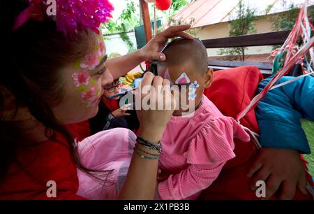 Bucarest, Roumanie. 17 avril 2024 : un artiste peint le visage d'une fille lors de l'ouverture du Centre de jour pour les enfants réfugiés d'Ukraine dont les mères travaillent ou veulent trouver un emploi. Le centre est ouvert par la Fondation Save the Children Roumanie pour 40 enfants, âgés de 6 à 11 ans, et pour soutenir les mères réfugiées d'Ukraine afin qu'elles puissent laisser leurs enfants en toute sécurité pendant qu'elles sont au travail, compte tenu du fait que trois parents ukrainiens sur cinq ne pouvaient pas trouver d'emploi en Roumanie, la plupart d'entre eux invoquant la barrière de la langue ou la nécessité de s'occuper d'un membre de la famille. Depuis l'épidémie Banque D'Images