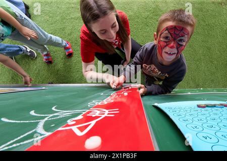 Bucarest, Roumanie. 17 avril 2024 : un garçon ukrainien joue avec un bénévole lors de l'ouverture du Centre de jour pour les enfants réfugiés d'Ukraine dont les mères travaillent ou veulent trouver un emploi. Le centre est ouvert par la Fondation Save the Children Roumanie pour 40 enfants, âgés de 6 à 11 ans, et pour soutenir les mères réfugiées d'Ukraine afin qu'elles puissent laisser leurs enfants en toute sécurité pendant qu'elles sont au travail, compte tenu du fait que trois parents ukrainiens sur cinq ne pouvaient pas trouver d'emploi en Roumanie, la plupart d'entre eux invoquant la barrière de la langue ou la nécessité de s'occuper d'un membre de la famille. Depuis l'outbr Banque D'Images