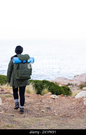 Randonneur féminin biracial avec les cheveux noirs marche près de la mer, entouré par la nature, l'espace de copie Banque D'Images