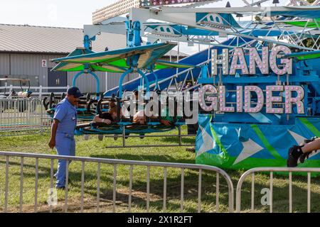 L'opérateur de divertissement de carnaval assiste avec le mouvement du manège 'Hang Glider' à la foire du comté d'Allen à Fort Wayne, Indiana, États-Unis. Banque D'Images