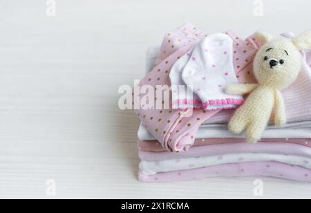 Pile de vêtements de bébé, chaussettes et jouet tricoté sur fond de bois blanc Banque D'Images