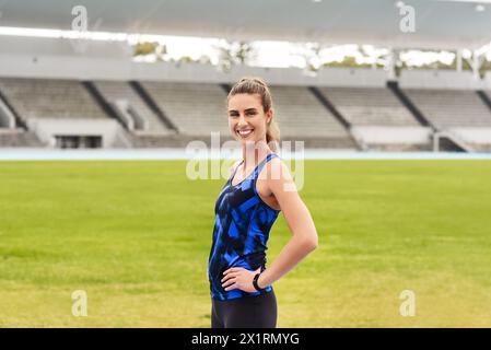 Fille, athlète et portrait heureux dans le stade pour la course de longue distance ou le sprint pour l'athlétisme et l'entraînement. Coureuse féminine, confiante et positive Banque D'Images