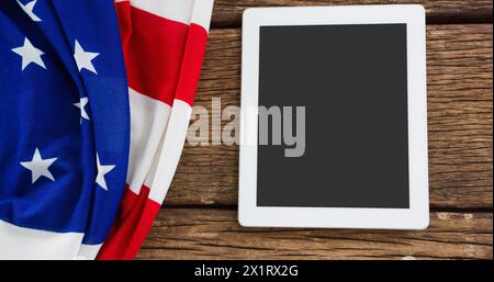 Drapeau américain drapé à côté d'une tablette blanche sur une surface en bois Banque D'Images