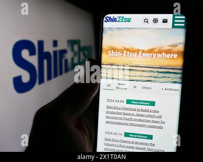 Personne tenant le smartphone avec la page Web de la société japonaise de produits chimiques Shin-Etsu Chemical Co. Ltd. avec logo. Concentrez-vous sur le centre de l'écran du téléphone. Banque D'Images