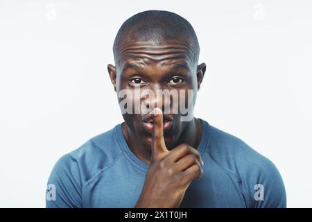 Homme noir, portrait et fitness avec secret pour l'entraînement, la routine ou la vie privée sur un fond blanc de studio. Visage de personne africaine ou masculine avec silence Banque D'Images
