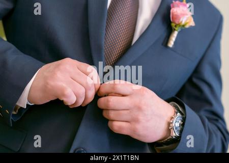 Bouton des mains des hommes de mariage vers le haut, Un homme dans un costume bleu attache un bouton, préparation pour un mariage Banque D'Images