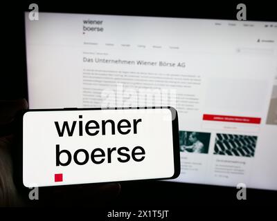 Personne détenant un smartphone avec le logo de la société boursière autrichienne Wiener Börse AG en face du site. Concentrez-vous sur l'affichage du téléphone. Banque D'Images