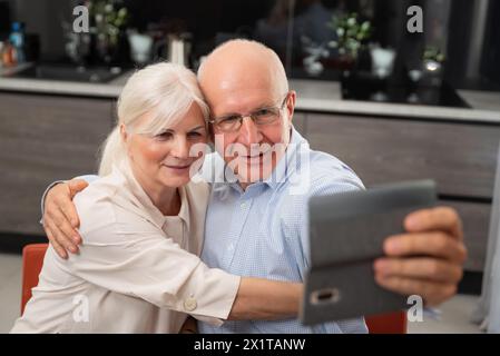 Couple senior souriant prenant selfie à la maison. Portrait de couple senior Banque D'Images