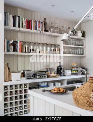 Bocaux de stockage et bouteilles de vin commandés sur les étagères de la cuisine à Chelsea Home, Londres, Royaume-Uni Banque D'Images