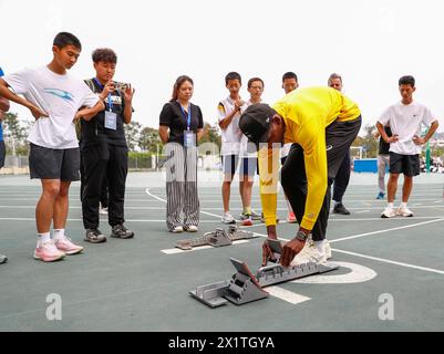 Xiamen, province chinoise du Fujian. 18 avril 2024. Le sprinter Fred Kerley (avant) des États-Unis ajuste un bloc de départ lors d'une activité de visite scolaire avant la réunion de la Wanda Diamond League Xiamen 2024 à Xiamen, dans la province du Fujian, au sud-est de la Chine, le 18 avril 2024. Crédit : HU Xingyu/Xinhua/Alamy Live News Banque D'Images