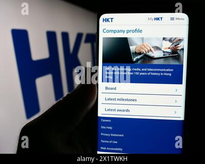 Personne tenant smartphone avec page Web de la société de télécommunications HKT Limited (Hong Kong Telecom) avec logo. Concentrez-vous sur le centre de l'écran du téléphone. Banque D'Images