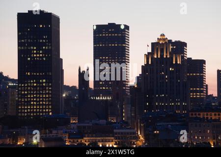 Édifices aux silhouettes et basilique historique notre-Dame, édifice art déco Aldred et gratte-ciel modernes illuminés au crépuscule, Vieux-Montréal, Québec Banque D'Images