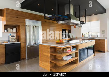 Cuisine avec îlot en bois de noyer américain, armoires et comptoirs en quartzite à l'intérieur de la maison moderne de style cube, Québec, Canada Banque D'Images