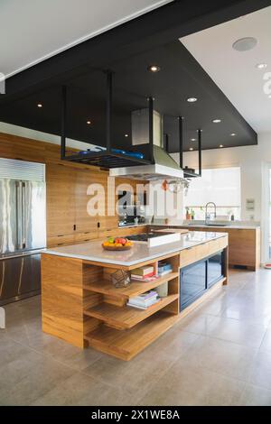 Cuisine avec îlot en bois de noyer américain, armoires et comptoirs en quartzite à l'intérieur de la maison moderne de style cube, Québec, Canada Banque D'Images