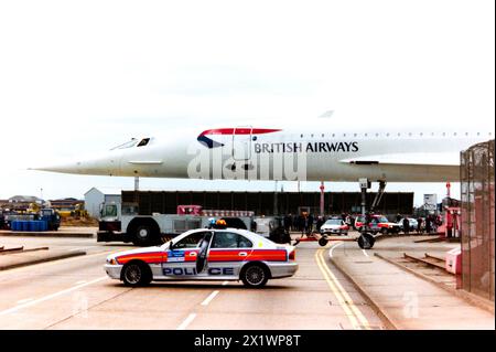 British Airways BAC Concorde G-BOAC est remorqué à travers Eastchurch Road à l'aéroport de Londres Heathrow, avec la route fermée par la police. La flotte de BA Concorde était stationnée dans son hangar de maintenance sur le périmètre de l'aéroport et remorquée dans la zone intérieure de l'aéroport lorsque nécessaire pour effectuer des vols réguliers. Des passionnés se sont rassemblés pour voir le Concorde vers la fin de son service nécessitant une plus grande présence policière. Il vola pour la première fois sous le nom de G-BOAC en 1975. Livré à British Airways en 1976. Il s'envole pour Manchester pour y être préservé et exposé le 31 octobre 2003 Banque D'Images