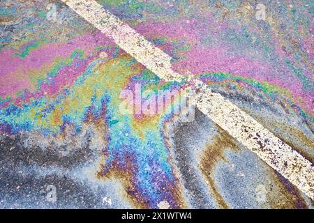 Déversement d'huile sur chaussée imbibée de pluie, parking avec lignes de séparation, accentuant les difficultés environnementales liées à la pollution de l'eau Banque D'Images