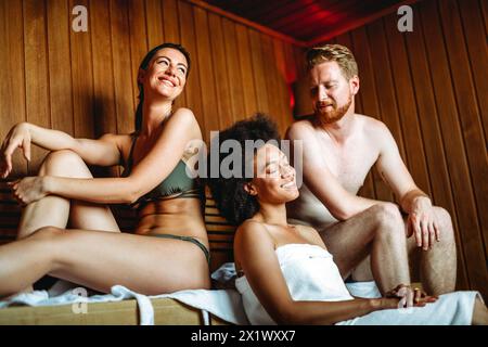 Profitez d'une journée de soins. Groupe d'amis heureux multiethniques se relaxant dans le sauna ensemble. Banque D'Images