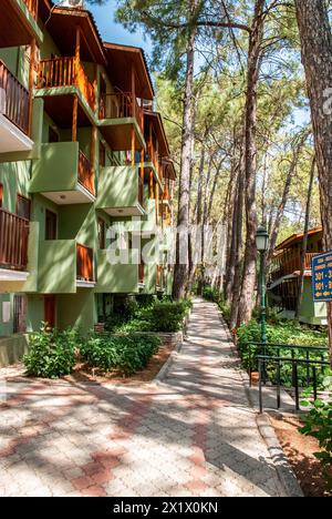 L'hôtel aux façades vertes et aux balcons en bois donne sur une passerelle pavée nichée au milieu des pins par temps ensoleillé Banque D'Images