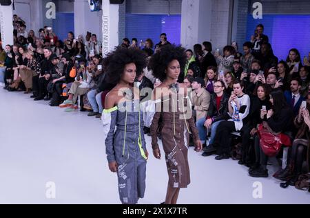 Des modèles jumeaux marchant dans la fosse de la passerelle pendant la semaine de la mode de Londres montrent des gens de foule afro la modélisation de la diversité Banque D'Images