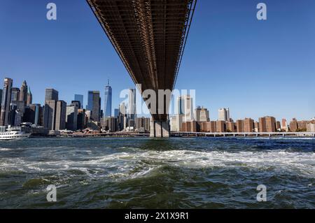 Sous le pont de Brooklyn regardant vers les gratte-ciel Lower Manhattan derrière East River depuis Brooklyn Bridge Park, Brooklyn, New York Banque D'Images
