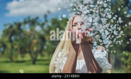 Une fille souffle des confettis en papier multicolores de ses mains. Banque D'Images