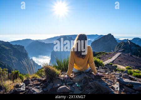 Description : femme toruiste est assise au sommet d'une montagne et profite de la vue sur le paysage d'une île volcanique par un après-midi d'été ensoleillé. Pi Banque D'Images