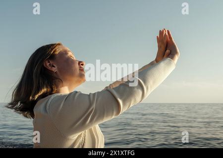 Une femme se tient confiante sur le pont d'un bateau, surplombant le vaste océan. Banque D'Images