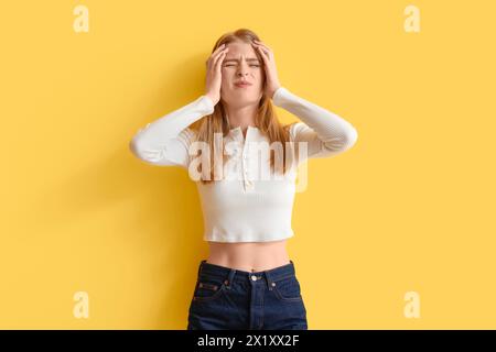 Jeune femme avec commotion cérébrale sur fond jaune Banque D'Images