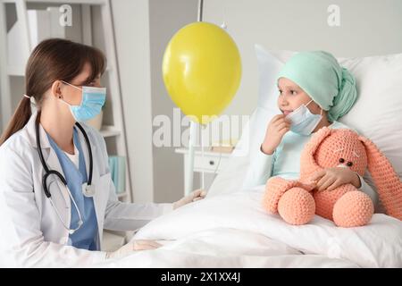 Petite fille après chimiothérapie recevant un ballon bleu du médecin en clinique. Journée internationale contre le cancer chez l'enfant Banque D'Images