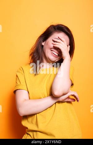 Femme adulte joyeuse aux cheveux bruns, rayonnant de bonheur par son sourire énergique et son expression joyeuse. Parfait pour mettre en valeur les émotions vibrantes d'un individu heureux. Banque D'Images