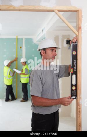 Travailleur avec équipement de protection, EPI, nivellement de la porte recadrage, construction de logement, niveau, pays basque, Espagne. Banque D'Images