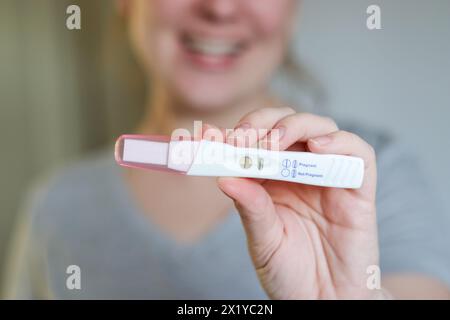 Gros plan d'une femme heureuse tenant un test de grossesse positif Banque D'Images