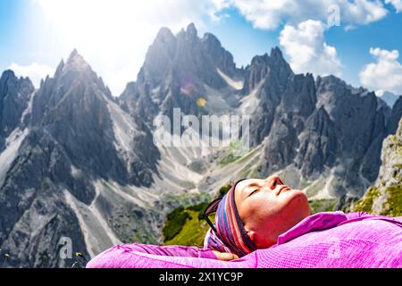 Description : jeune femme profite du bain de soleil avec vue épique sur la chaîne de montagnes Cadini di Misurina le matin. Tre Cime, Dolomites, Tyrol du Sud, Italie, E Banque D'Images